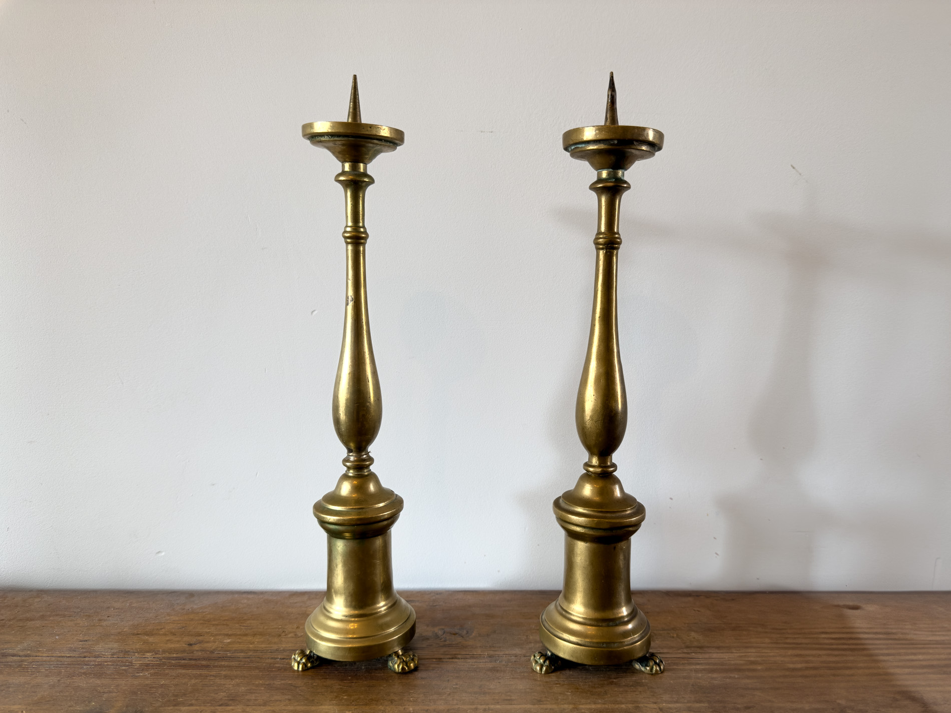 Pair of 18th-century bronze candlesticks with lion’s paw feet and classical design